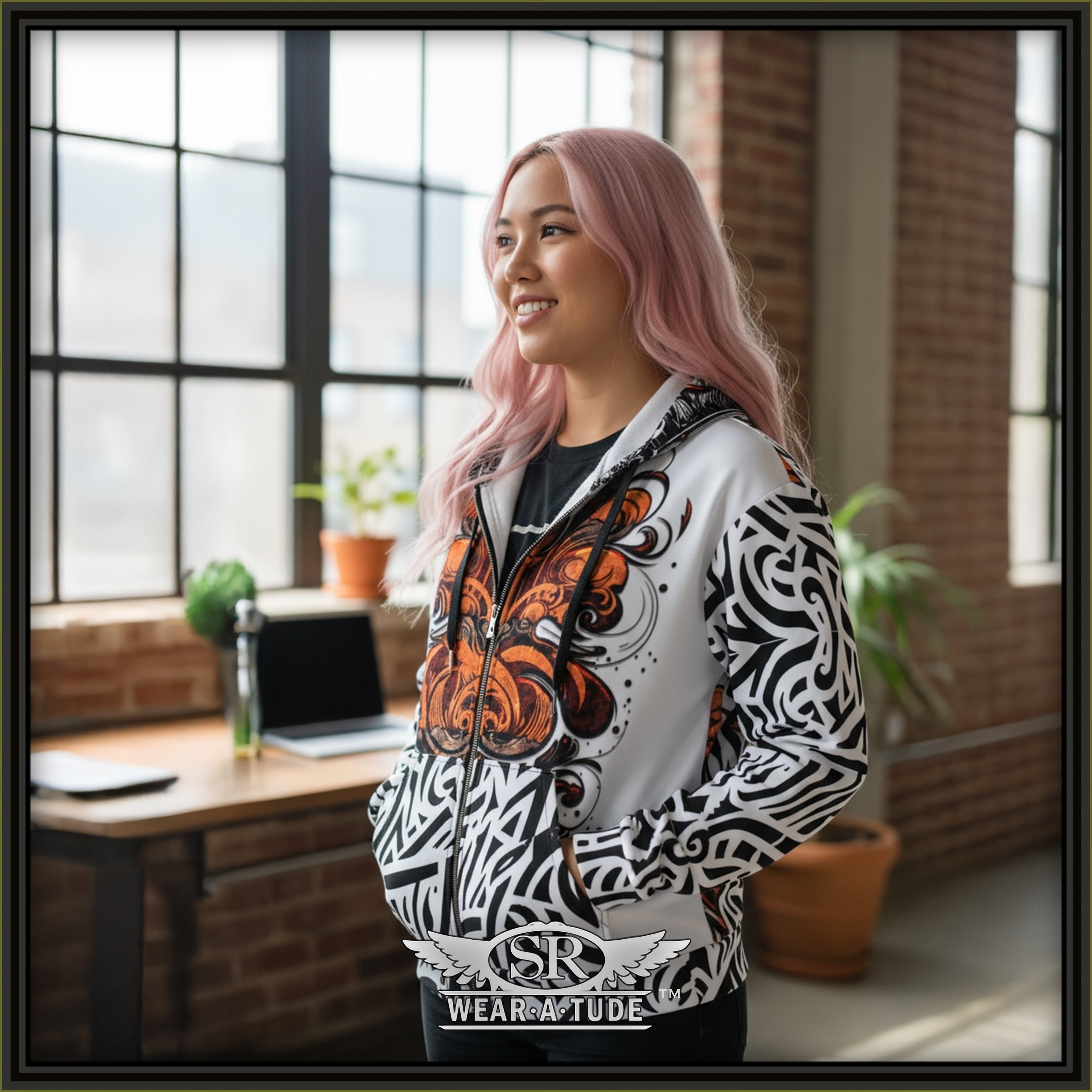 Young woman standing in a loft wearing the Santa Rebelde zipper hoodie. Bold black and white print hinting at a Chicano style with a abstract rust orange chest print